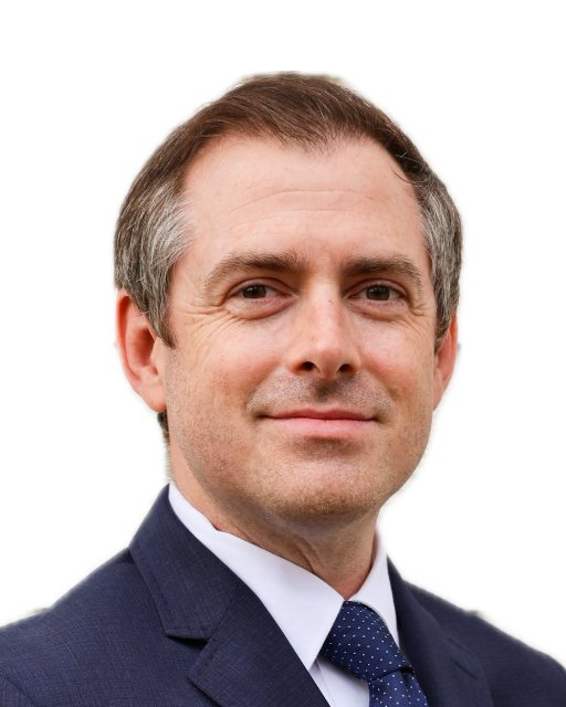Andrew Peppard, head and shoulders, in a navy suit and tie.